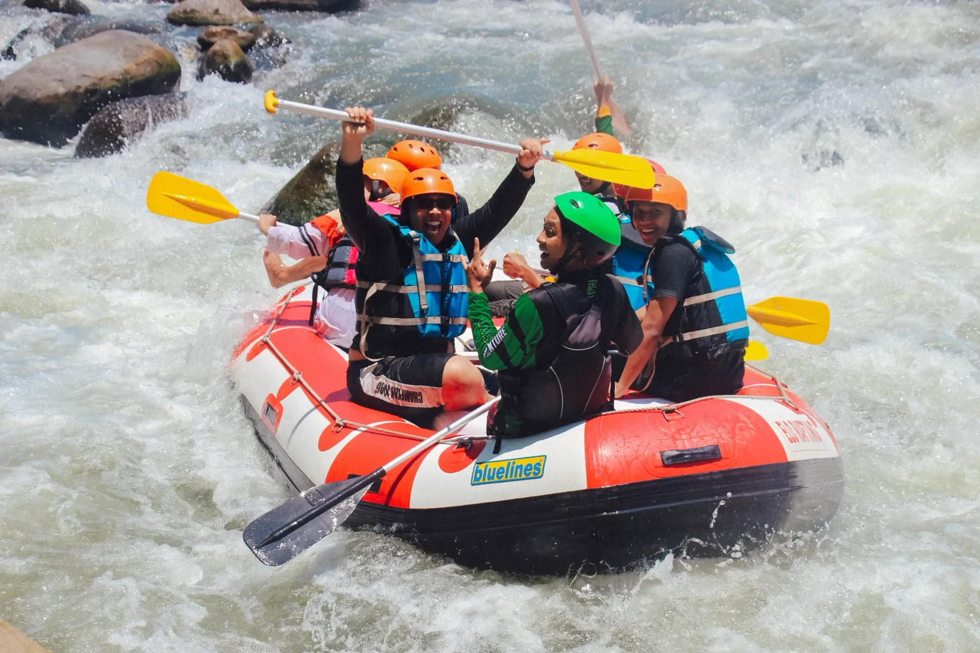 People whitewater rafting, paddling through rapids.