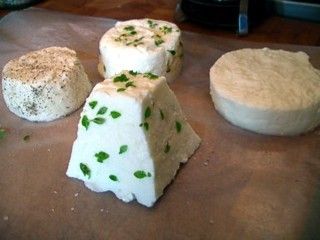 Four rounds of goat cheese with herbs and spices on parchment paper.