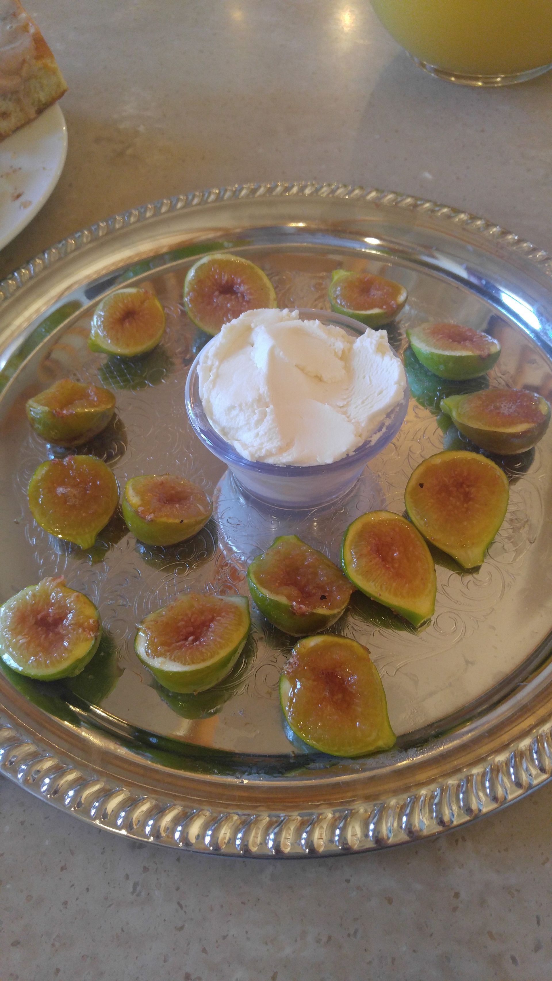 Silver platter with fig halves around a bowl of whipped cream.