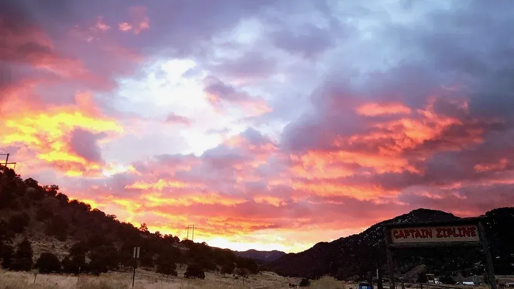 Fiery sunset over mountains; sign reads