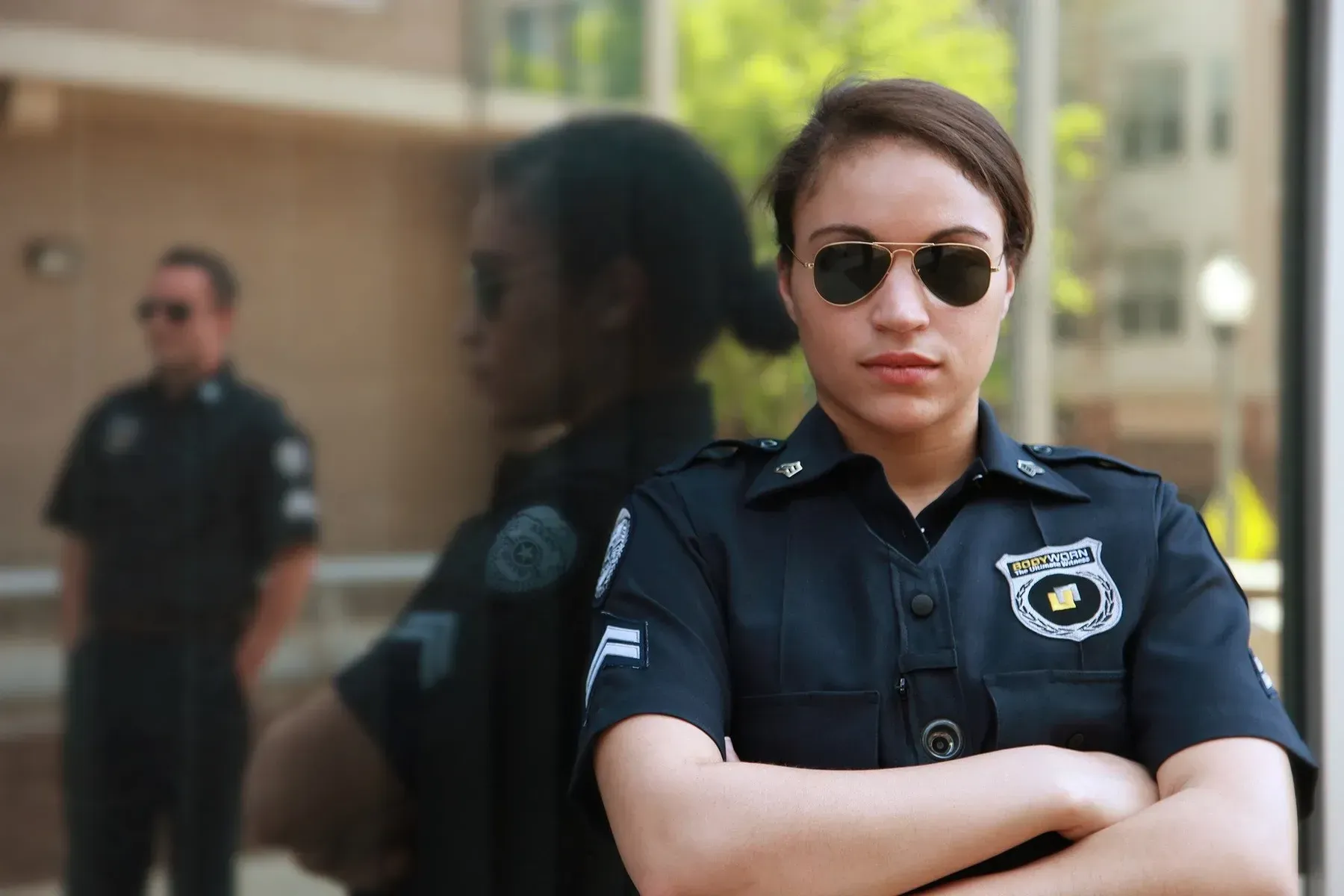 Female police officer wearing sunglasses, arms crossed,
