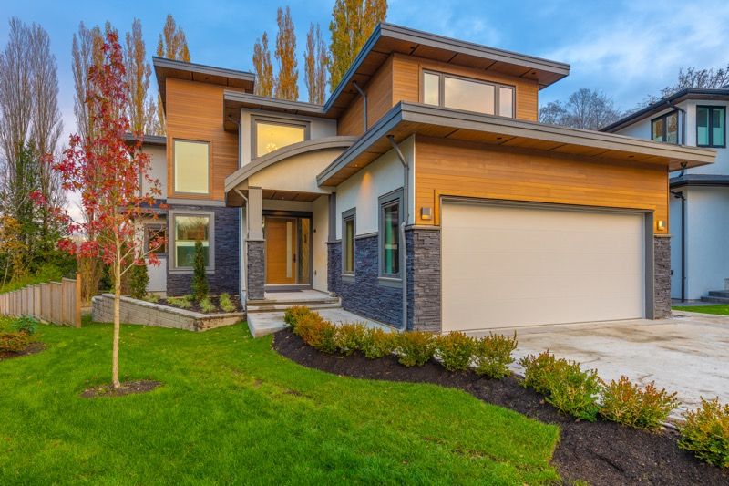 NW Contemporary two-story house with wood and stone accents, curved entryway, and two-car garage.