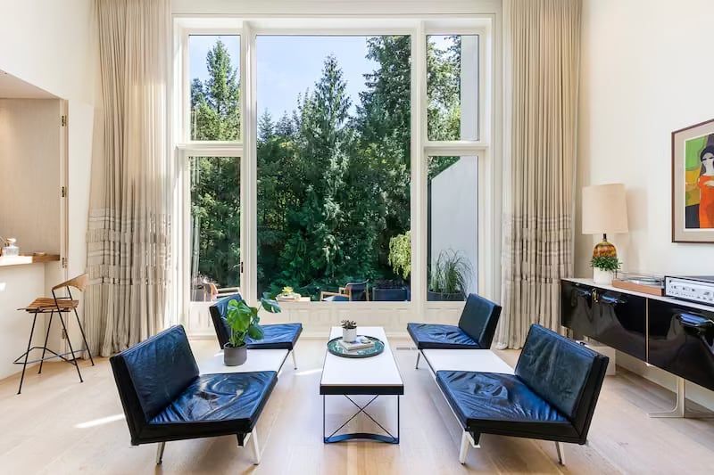 Living room with large window, modern furniture, and a view of trees.