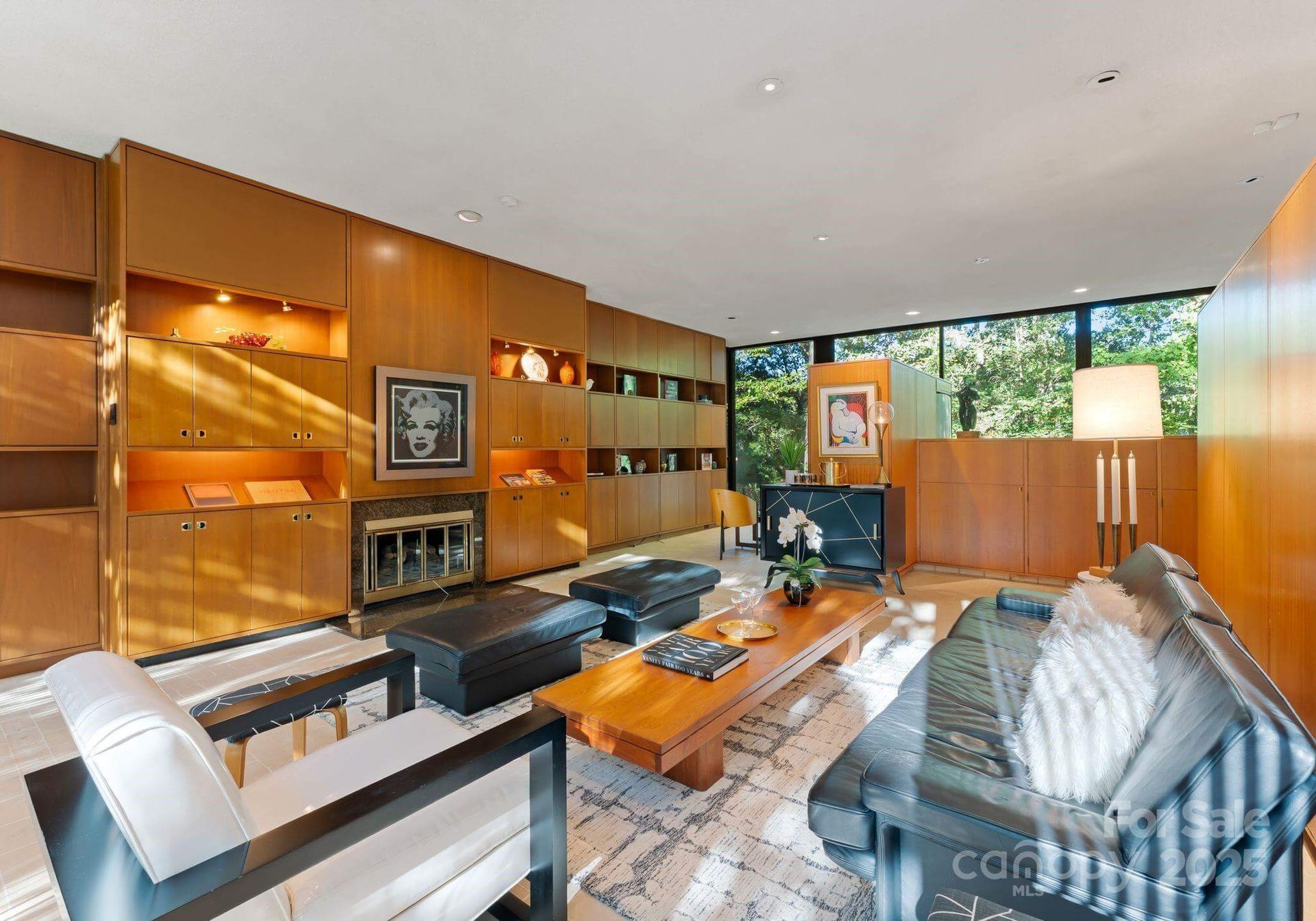 Living room with wood paneling, black leather furniture, and a large window.