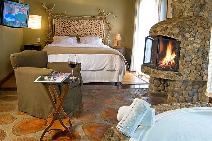 Um quarto com cama, cadeira, televisão e lareira.