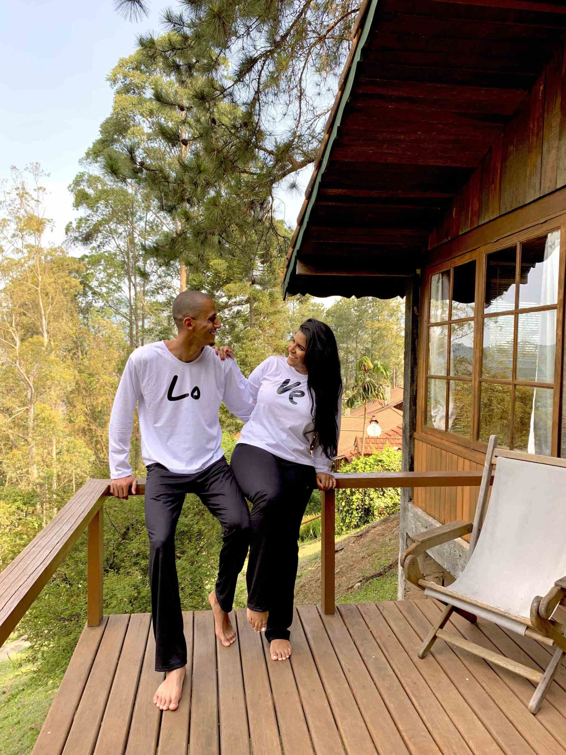 Um homem e uma mulher estão sentados em um deck ao lado de uma casa de madeira.