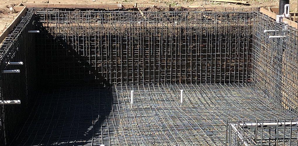 A large swimming pool is being built with a lot of wire mesh.