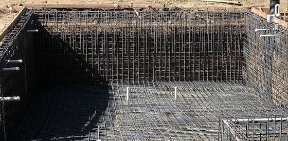 A large swimming pool is being built with a lot of wire mesh.