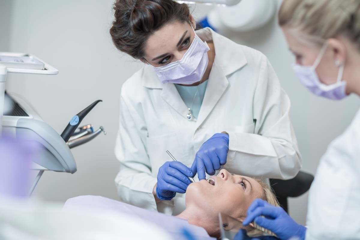 Dentist with assistant examining patient's teeth in a dental office.
