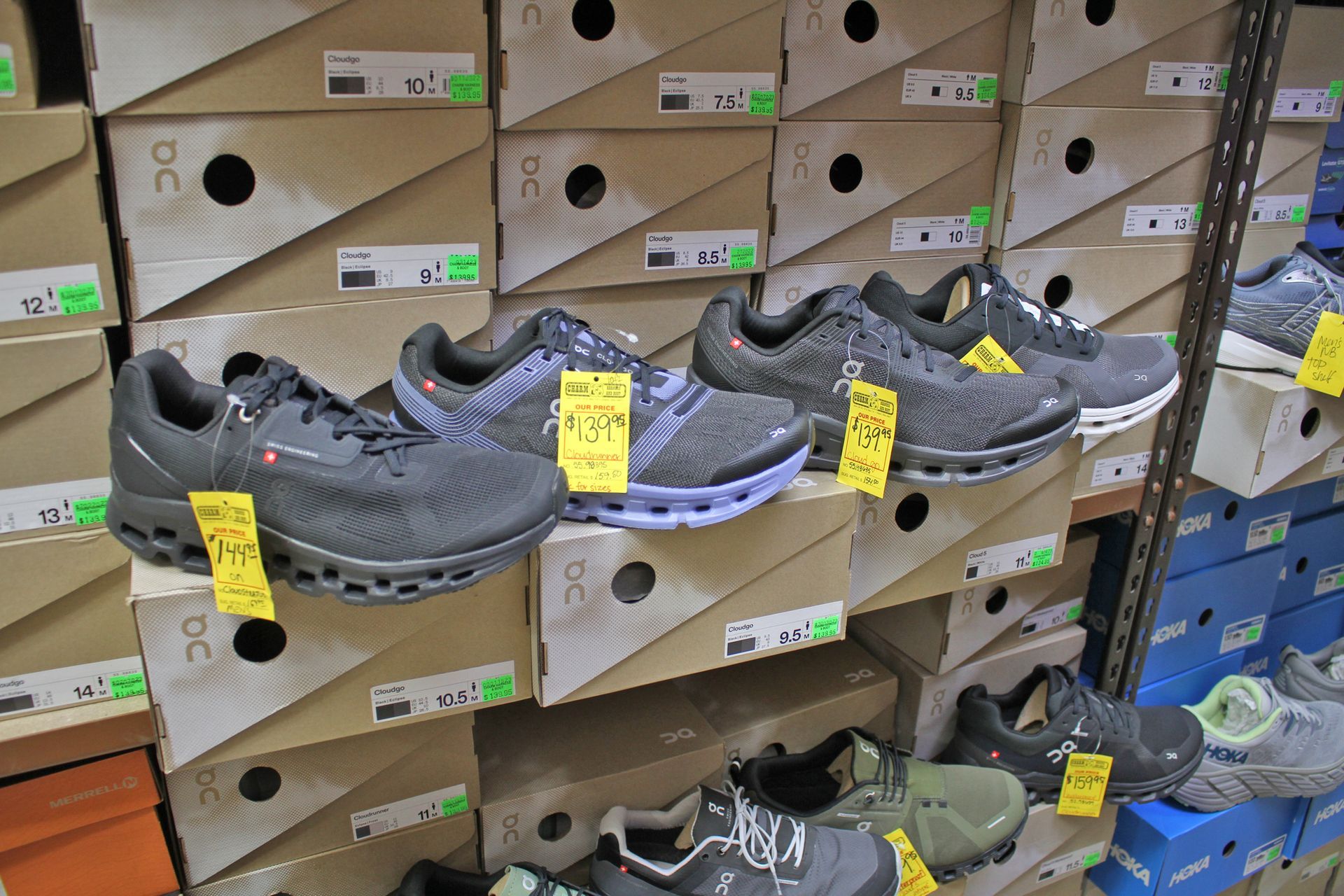 Shelves stocked with athletic shoes in boxes, some displayed, various colors and styles, retail setting.