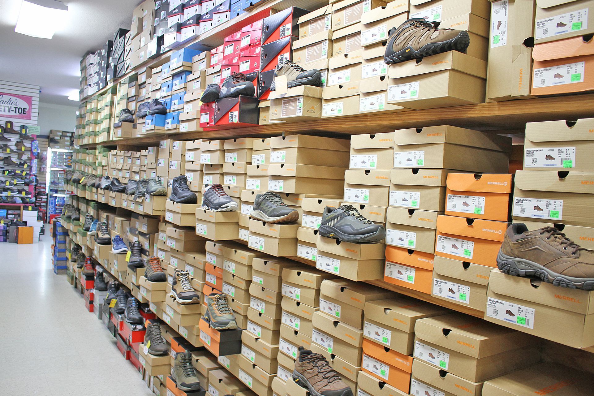 Shoe store interior with shelves packed with shoe boxes, some with displayed shoes.