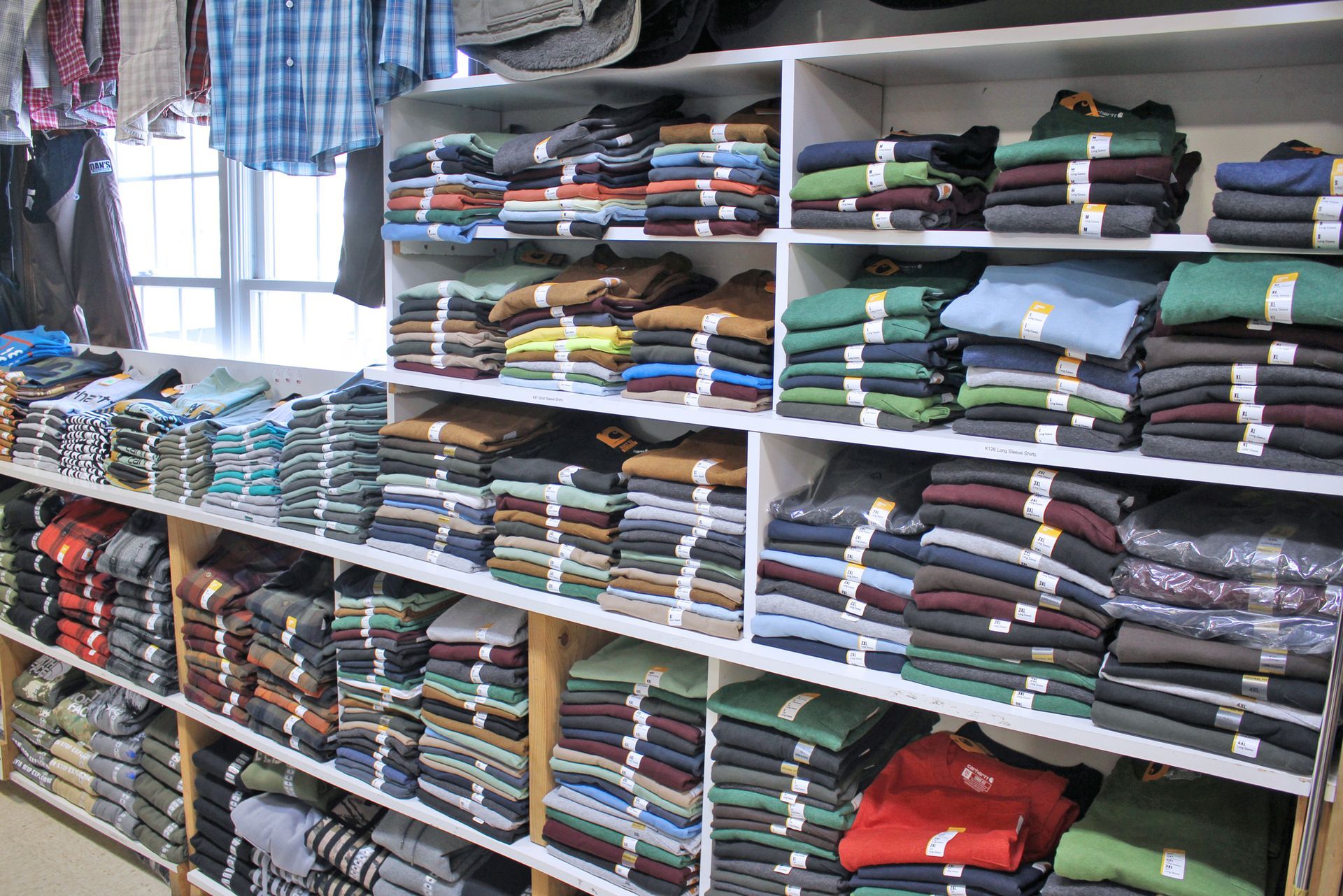 Shelves of folded clothing in various colors, inside a store.