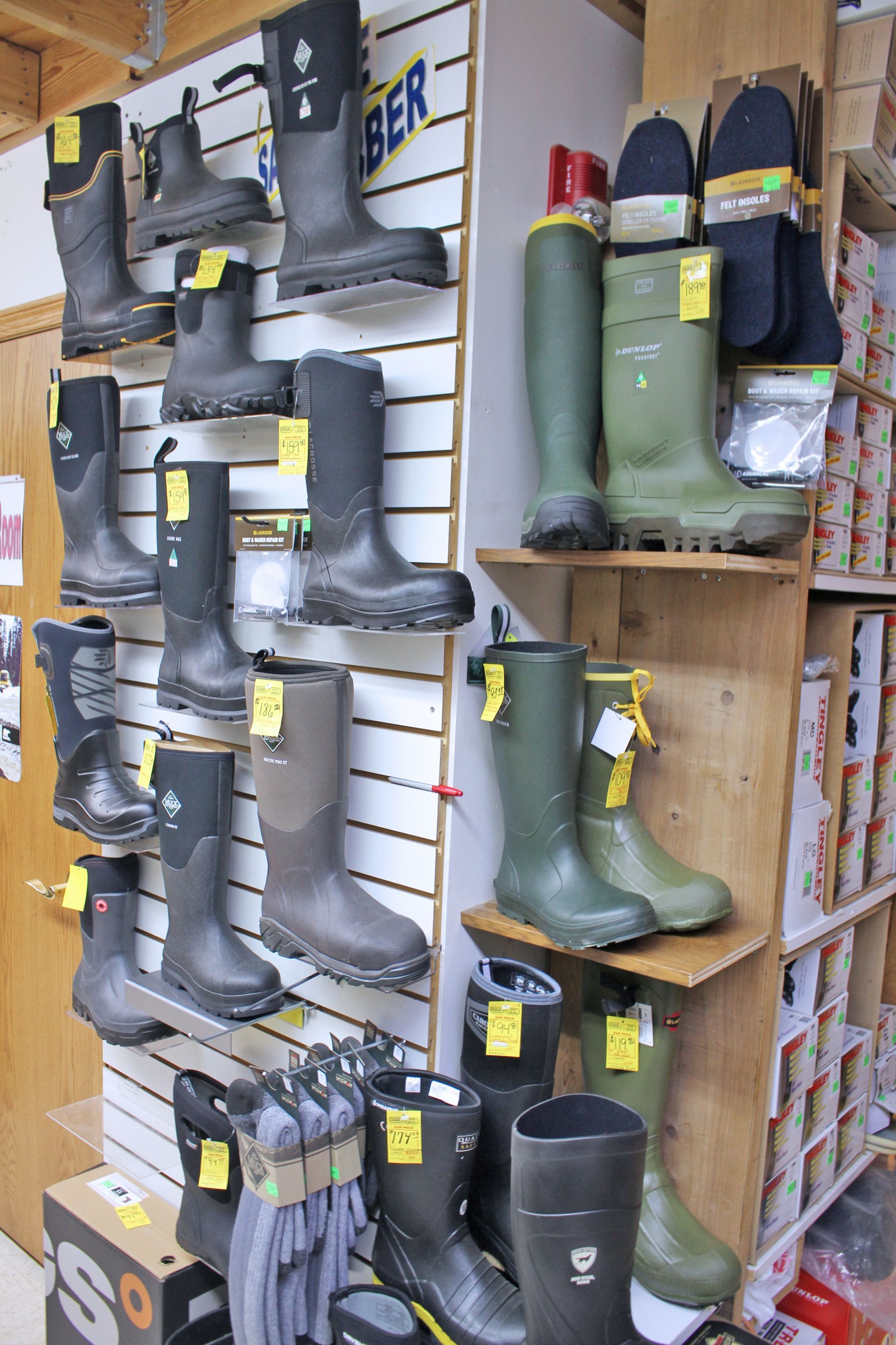 Boots on display shelves in a store. Various colors and styles, some with yellow price tags.