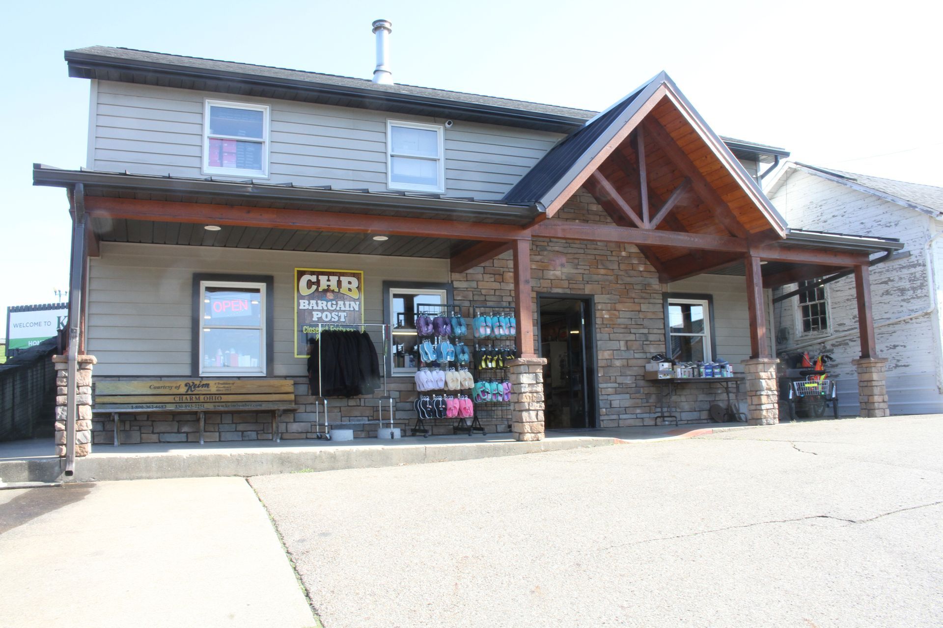 A two-story building with a covered porch and stone facade; store displays are visible.
