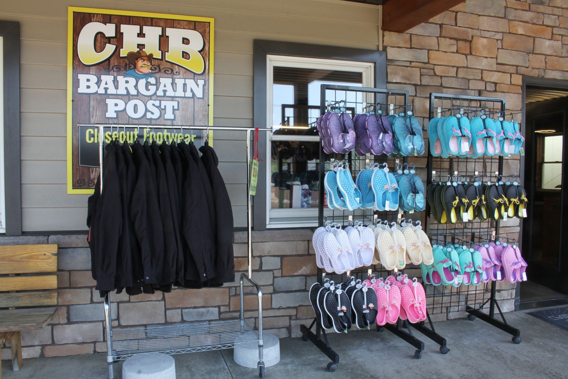 CHB Bargain Post storefront with clothing racks. Jackets hang left; sandals in various colors display right.