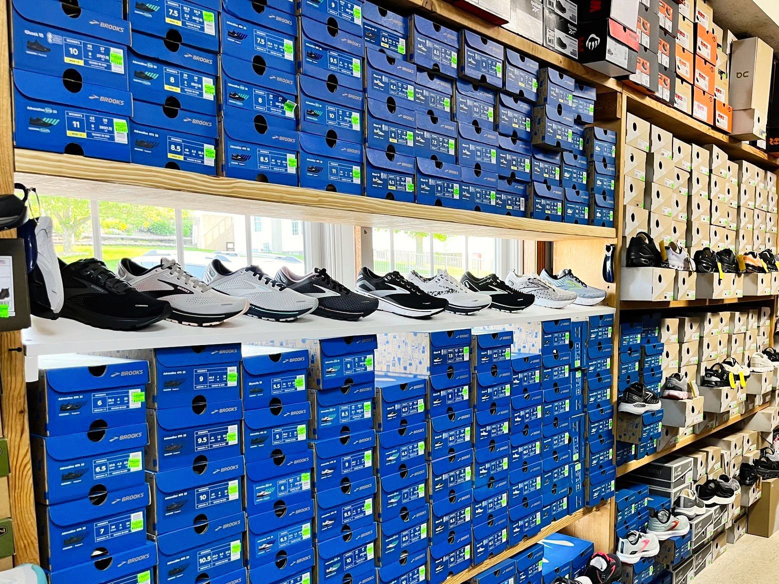 Shoe store interior with rows of blue and white shoe boxes on shelves, and various shoes on display.
