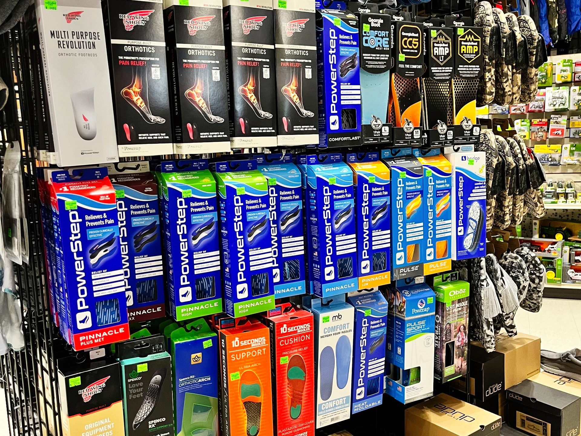 Display of shoe inserts and support braces in a store. Products are in various colors and packaging.