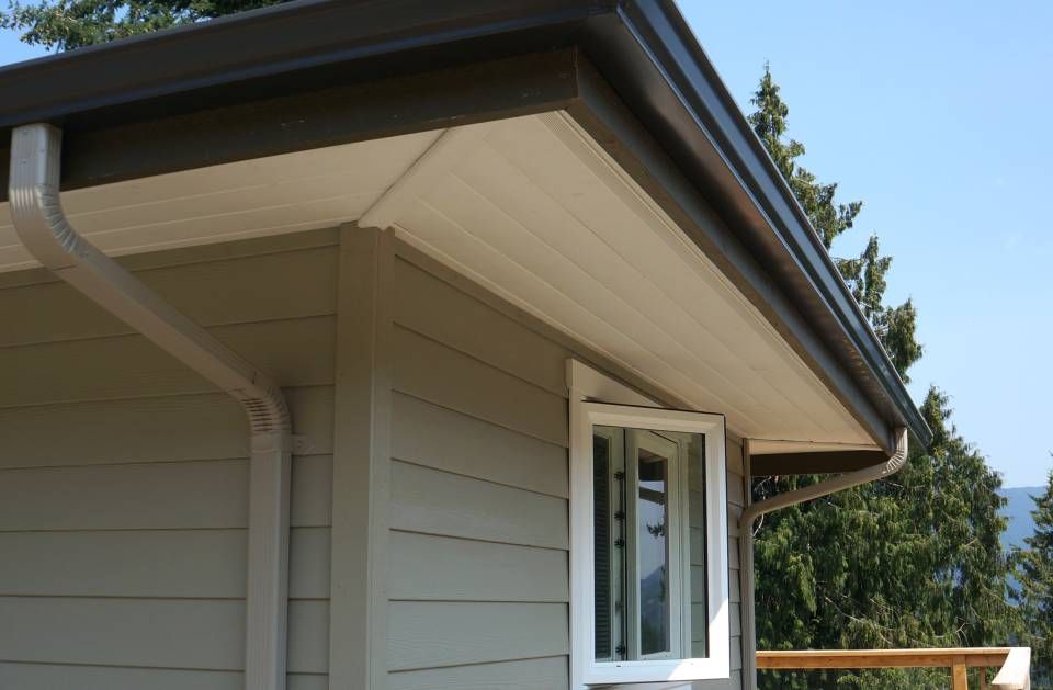 Exterior corner of a building with brown gutters, beige siding, and an open window.