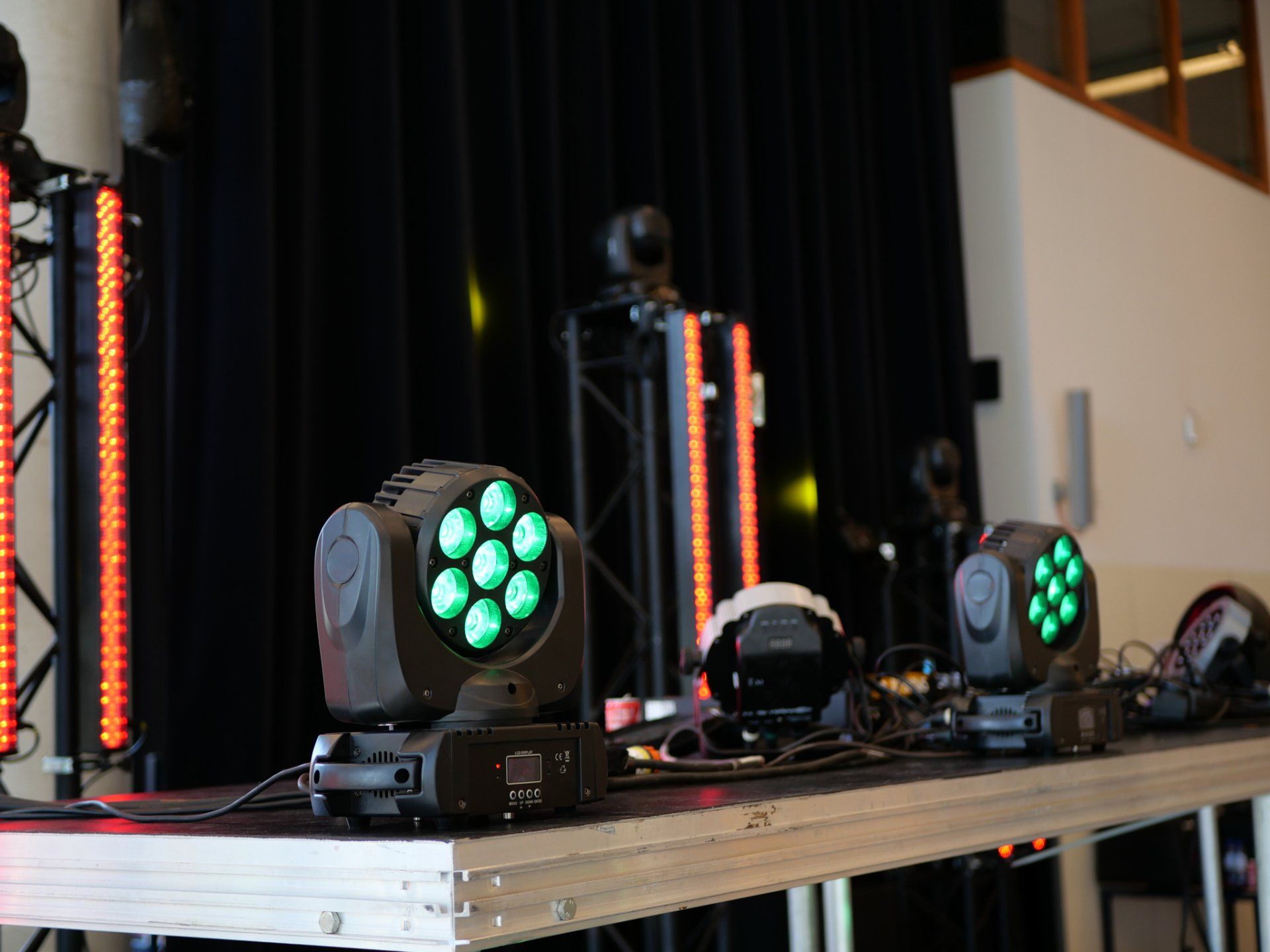Podiumverlichting met groene spotlights en oranje ledstrips op een zwarte achtergrond.