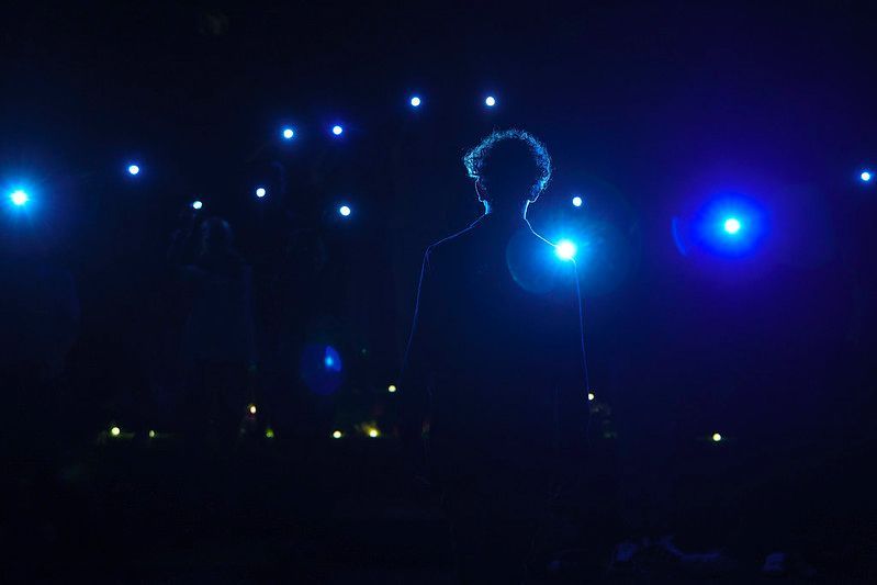 Silhouet van een persoon met krullend haar, voor blauw licht in de nacht.