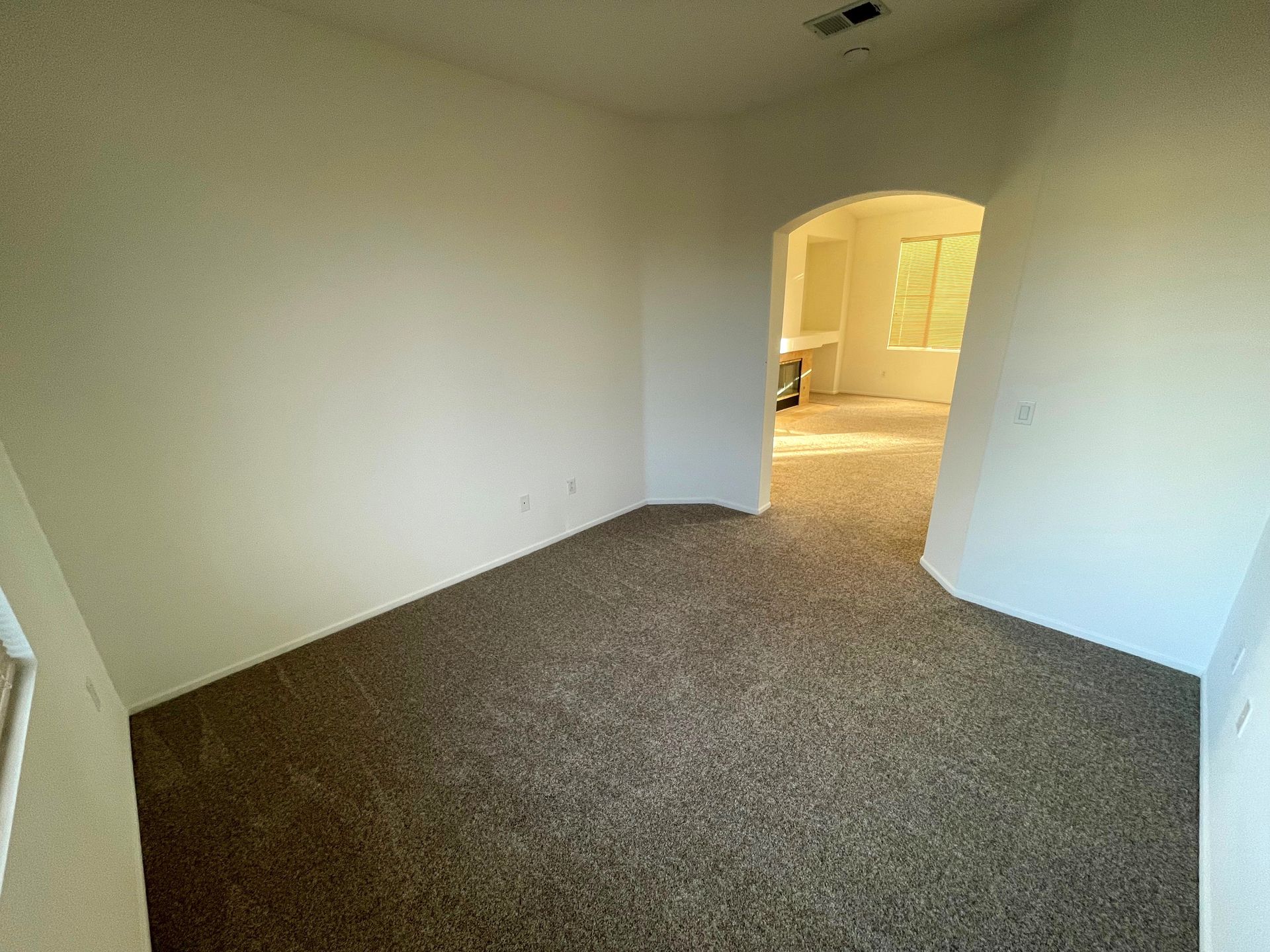 An empty bedroom with a brown carpet and white walls.