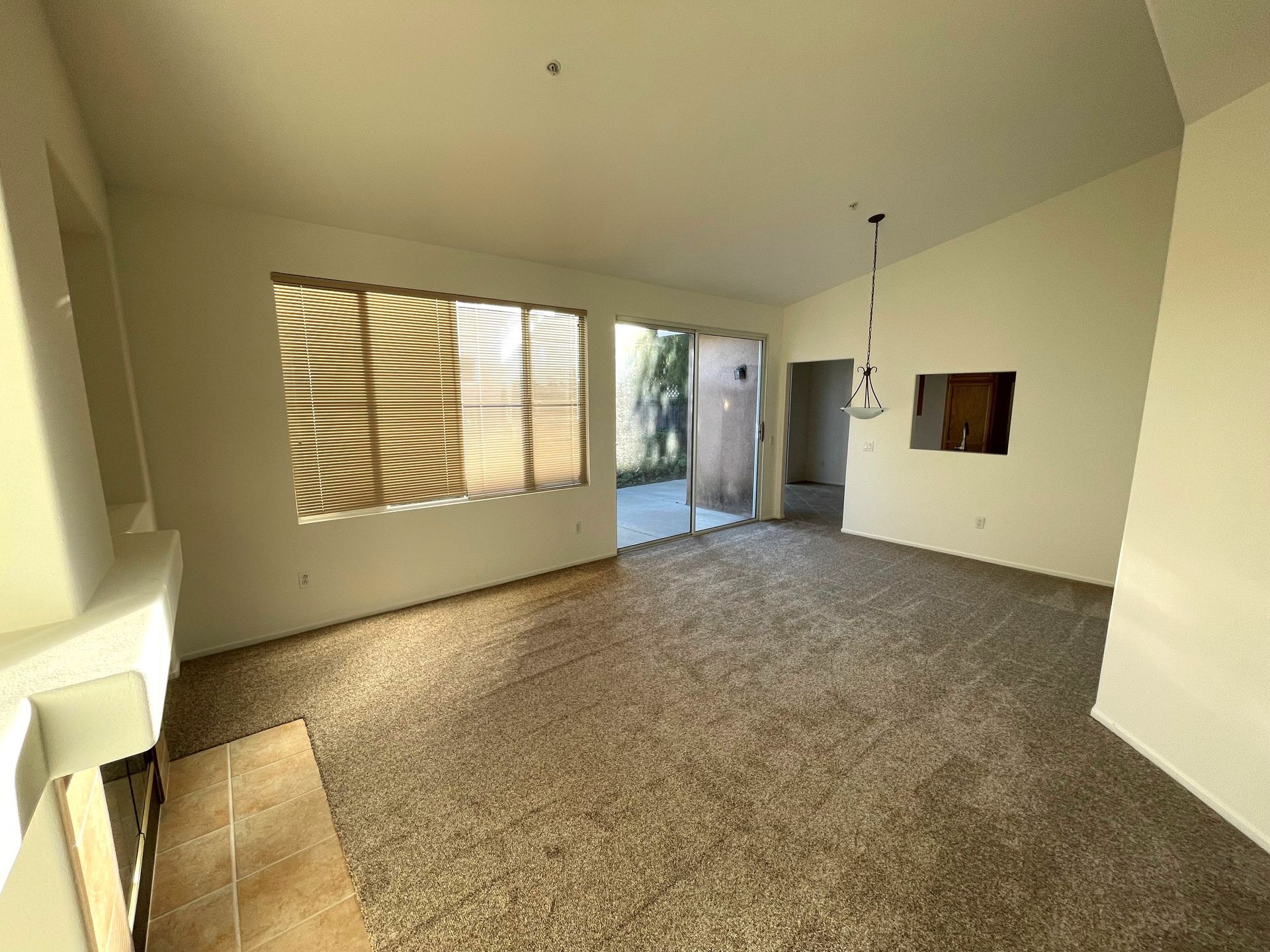An empty living room with a sliding glass door and a fireplace.