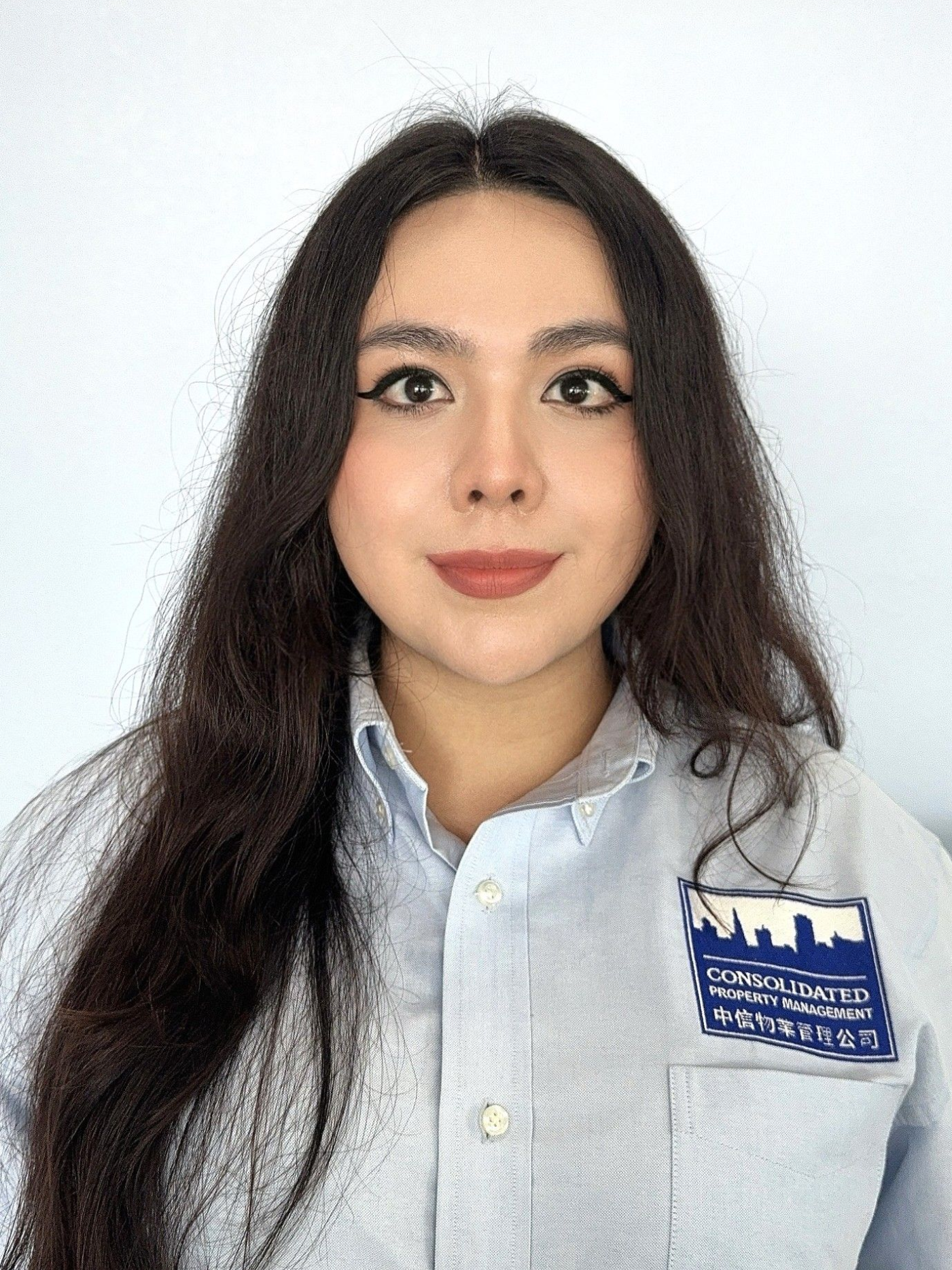 A woman with long hair is wearing a blue shirt and a name tag.