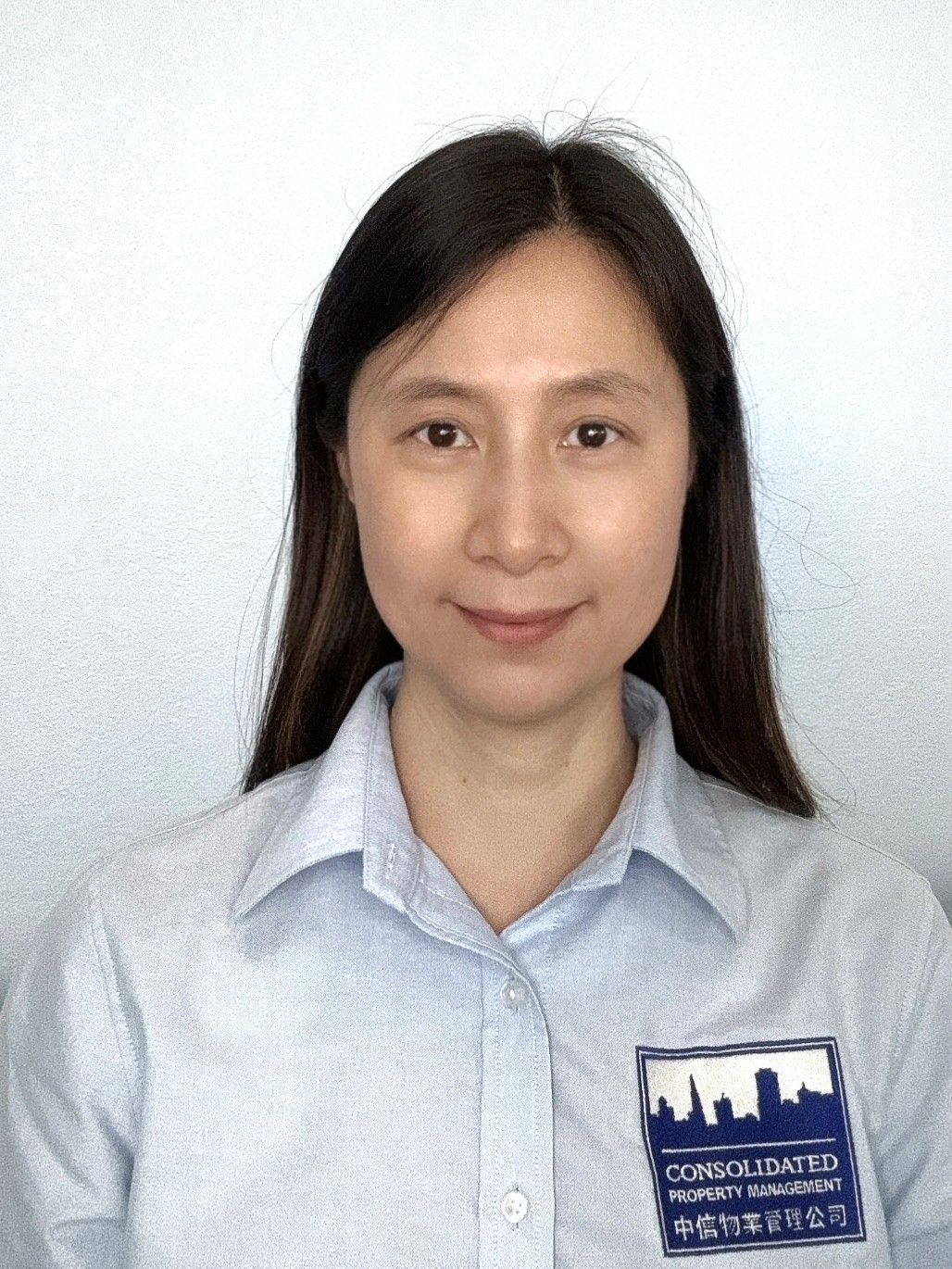A woman with long hair is wearing a blue shirt and smiling for the camera.