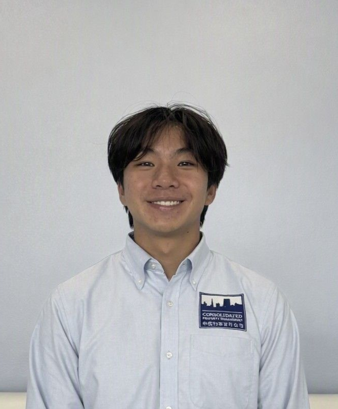 A young man wearing glasses and a grey shirt is looking at the camera.
