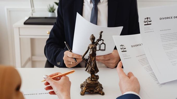 Abogados revisando documentos alrededor de una estatua de la Dama de la Justicia en un escritorio