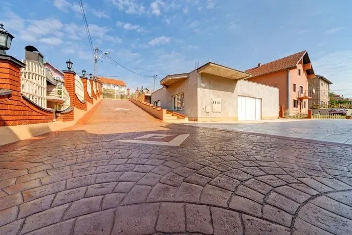 Sunlit cobblestone courtyard with orange walls and parked cars by houses