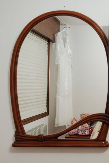 Ingelijste trouwjurk in een diepe lijst aan de muur