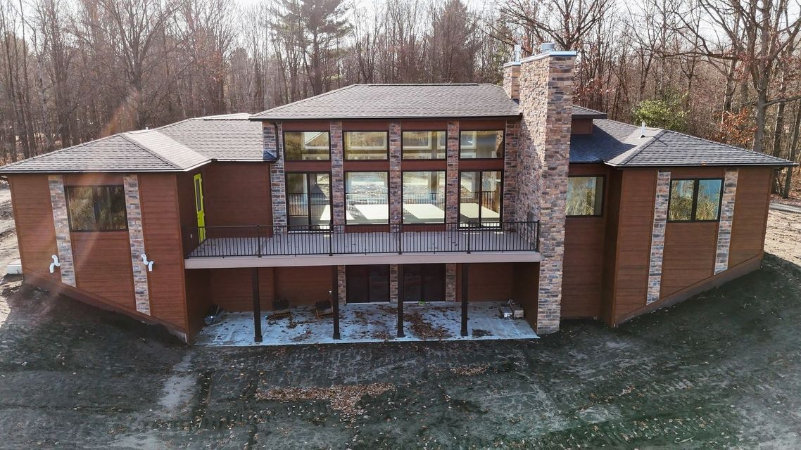 Modern brick house with large windows, central chimney, and a covered patio in a wooded setting