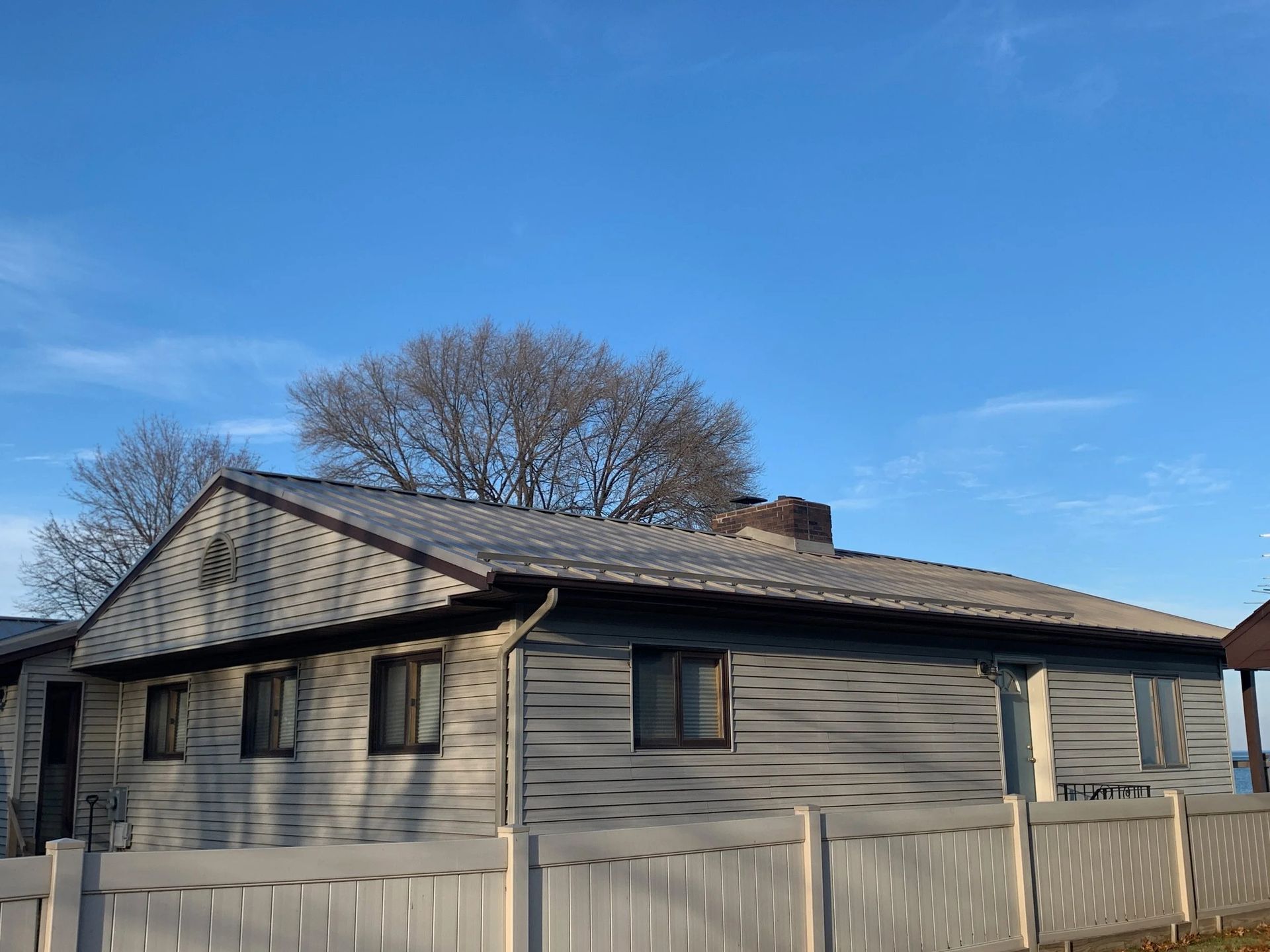 Gray house with a fenced yard under a clear blue sky