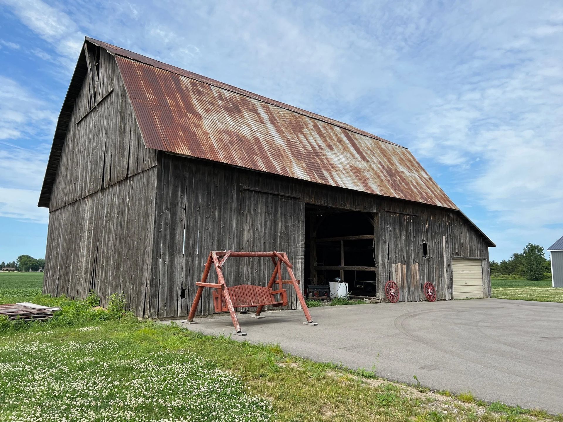 Old weathered barn with rusted roof and open doorway on a rural roadside.