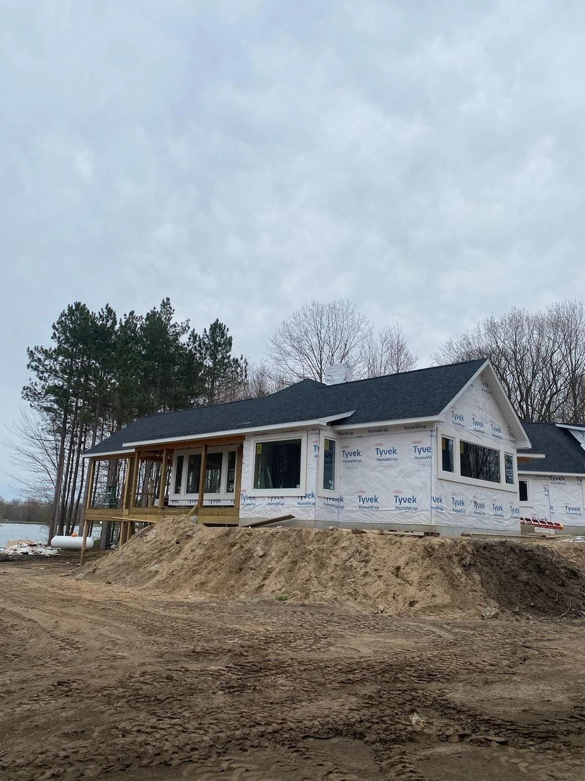 Partially built white house on a dirt lot under a cloudy sky