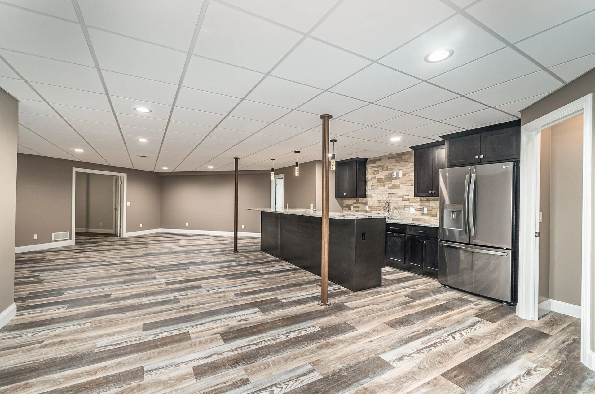 Modern open-concept kitchen and living area with dark cabinetry, stainless appliances, and striped flooring