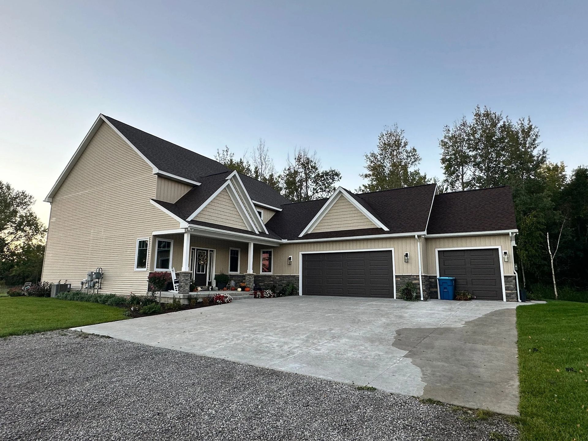 Large beige suburban house with attached garage and wide concrete driveway at dusk