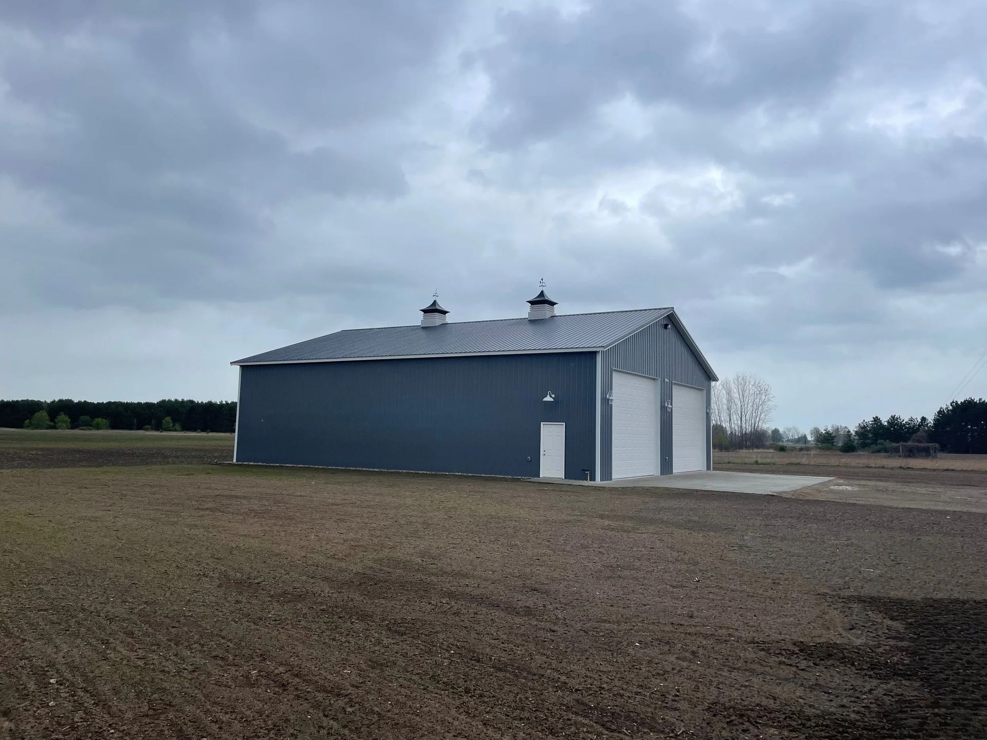 Gray barn-like building on a barren field under a cloudy sky