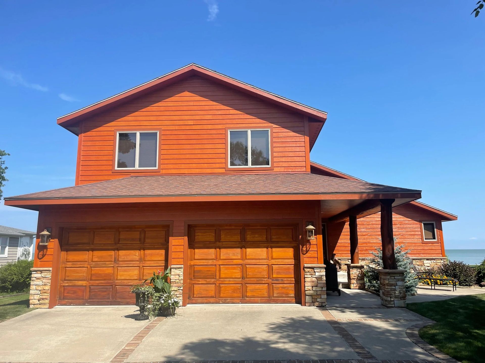 Orange two-story house with twin garage doors and a covered front porch under a blue sky