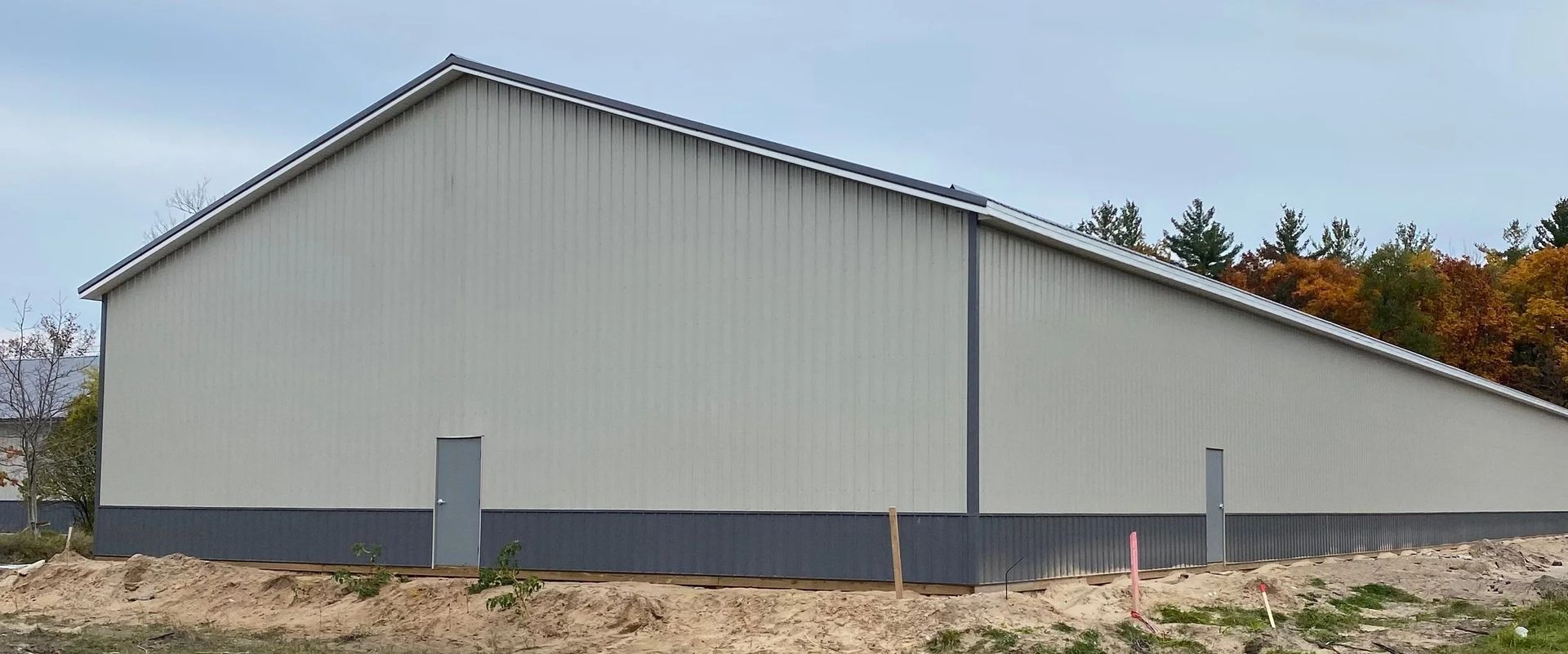 Side view of a large gray metal warehouse with a sloped roof and small side door.