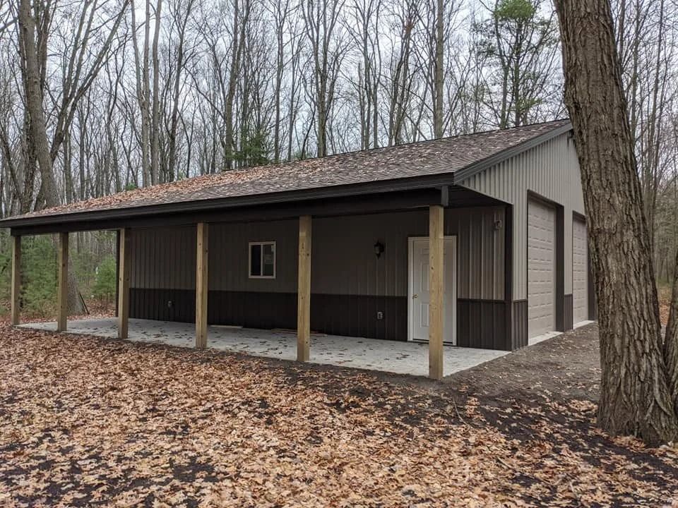 Small dark cabin with porch in a leaf-covered wooded area