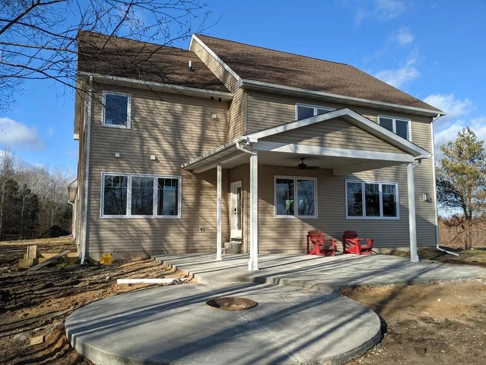 New tan house with a covered front porch and curved concrete walkway under construction
