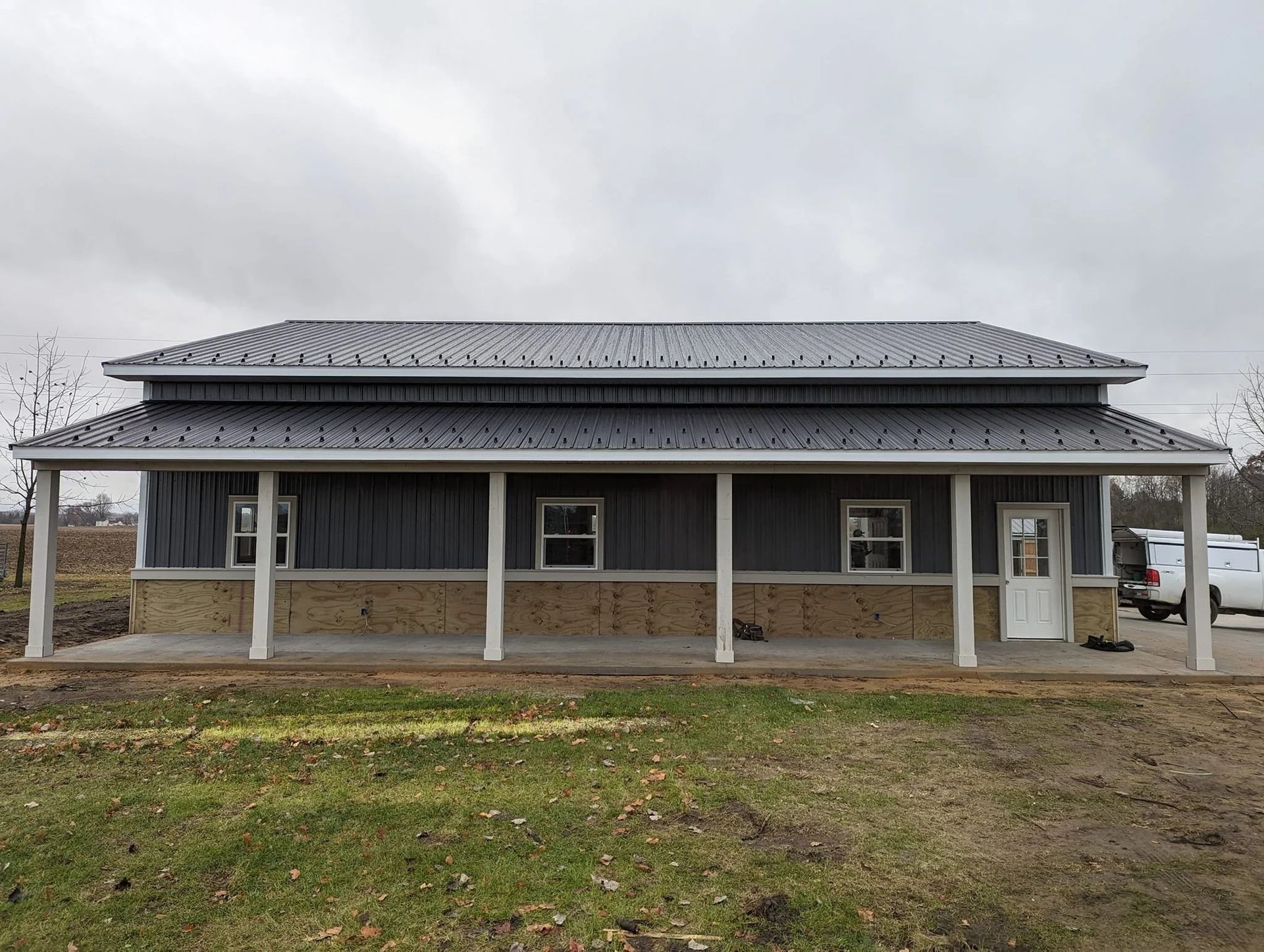 Gray building with a covered porch and white columns under an overcast sky