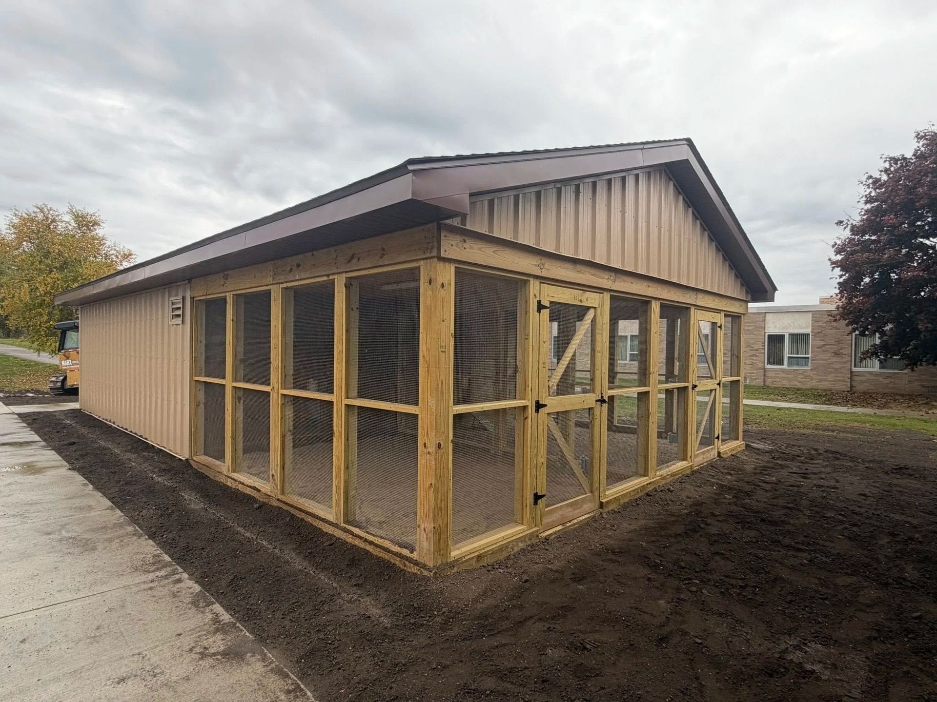 New wooden shed with screened porch under construction beside a driveway