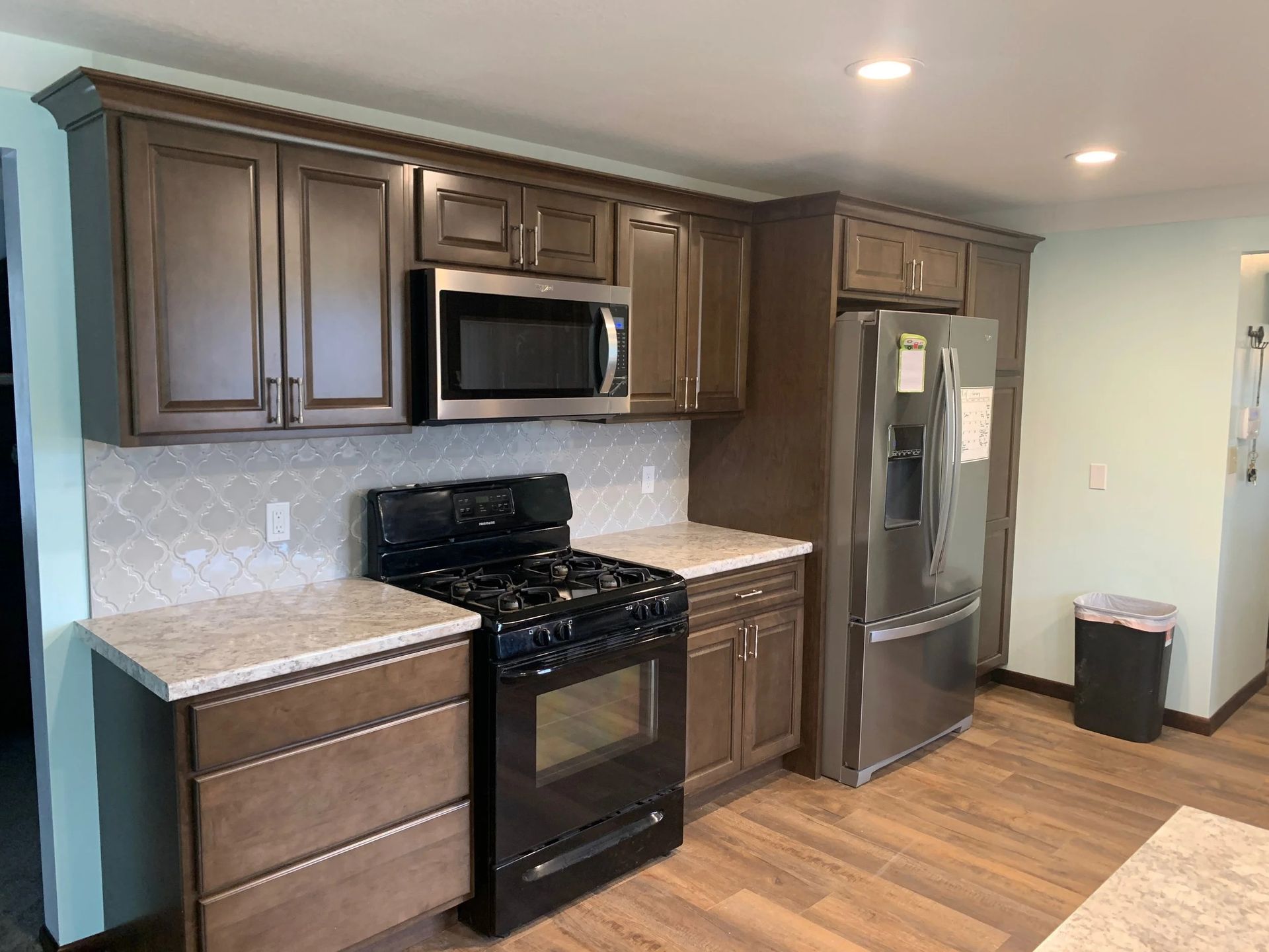 Modern kitchen with dark wood cabinets, stainless steel appliances, and wood flooring