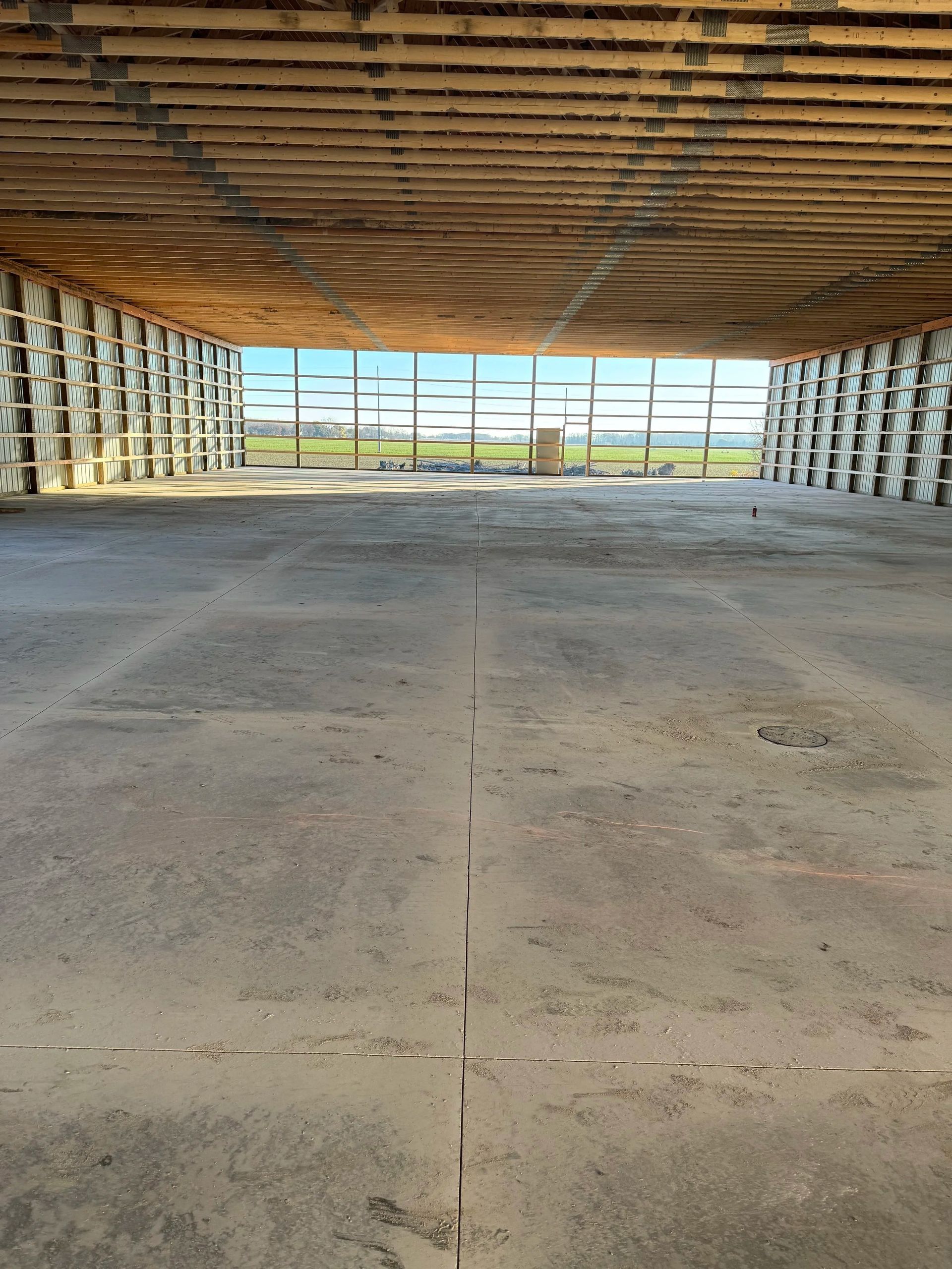 Empty warehouse interior with exposed wooden ceiling and open view through large end windows