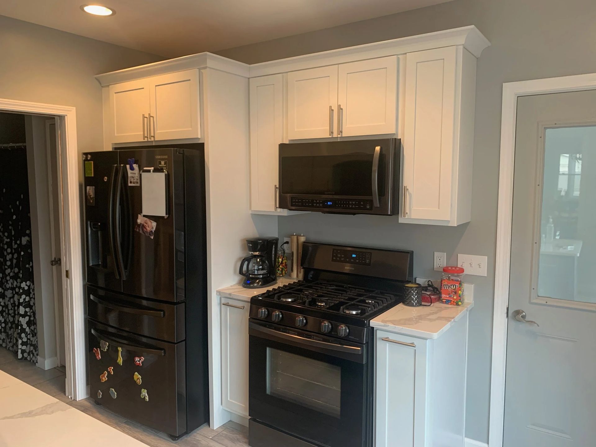 Modern kitchen with black appliances, white cabinets, and light gray walls