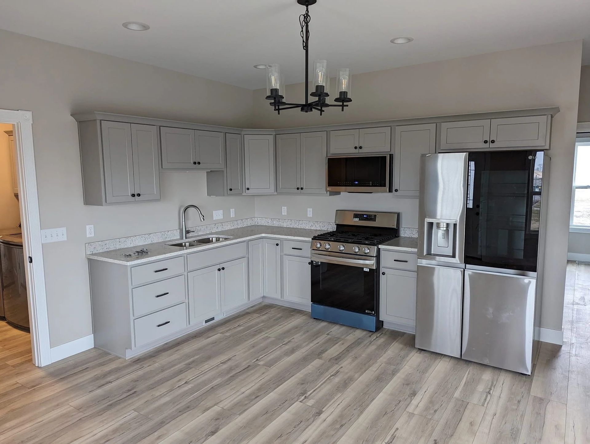 Modern kitchen with gray cabinets, stainless appliances, and light wood flooring