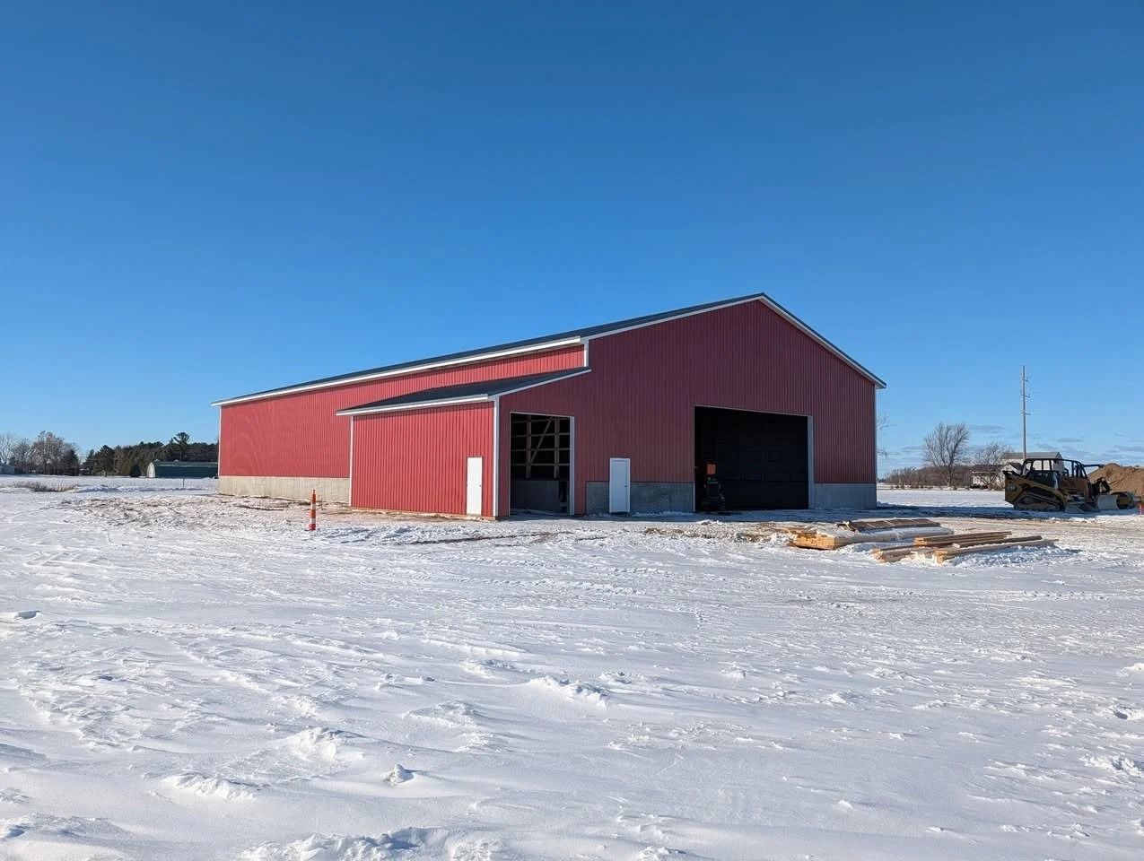 Red barn-style building on a snowy field under a clear blue sky